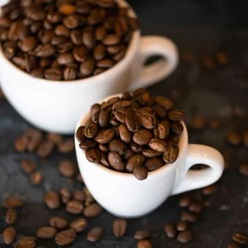 Top view of Cups with roasted coffee beans. Close up shot. Two white cups, small Stock Photos