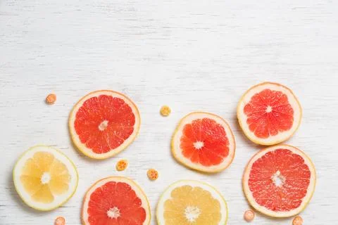 Top view on cut red and yellow grapefruit and small citrus candies on white w Stock Photos
