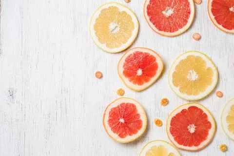 Top view on cut red and yellow grapefruit and small citrus candies on white w Stock Photos