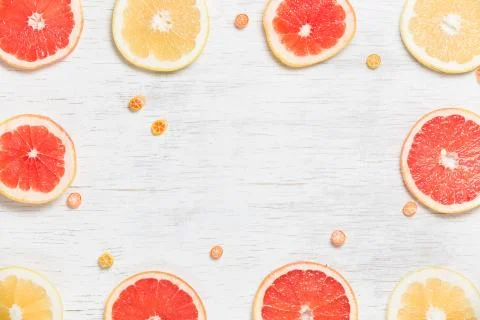 Top view on cut red and yellow grapefruit and small citrus candies on white w Stock Photos