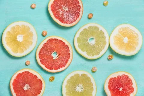 Top view on cut red and yellow grapefruit and small citrus candies on white w Stock Photos