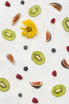 Top view on cut summer fruit (figs, kiwi, raspberries, blueberries) and flowe Stock Photos