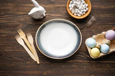 Top view of cutlery set with Easter eggs on wooden table, space for text. Eas Stock Photos