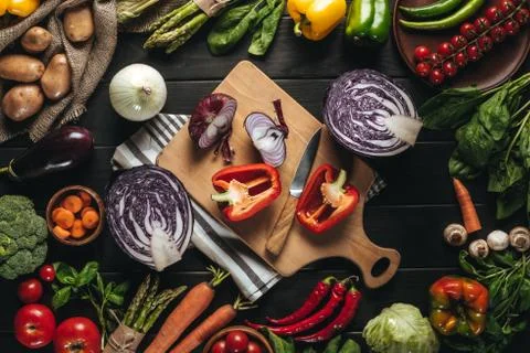 Top view of cutting board with knife and organic fresh vegetables on wooden t Stock Photos