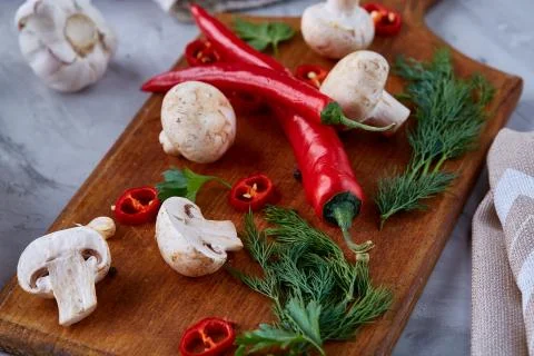 Top view of cutting board, vegetables and herbs on wooden tabletop, selective Stock Photos