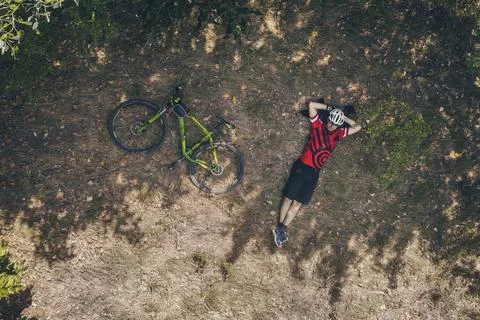 Top view of a cyclist resting lying on the grass with his bicycle next to him Stock Photos