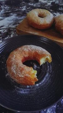 A top view of a dark surface covered in flour, with several uncooked doughnuts Stock Photos