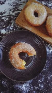 A top view of a dark surface covered in flour, with several uncooked doughnuts Stock Photos