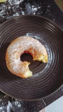 A top view of a dark surface covered in flour, with several uncooked doughnuts Stock Photos