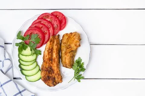 Top view of deep fried hake fish with vegetables served on a plate on white Stockfoto's