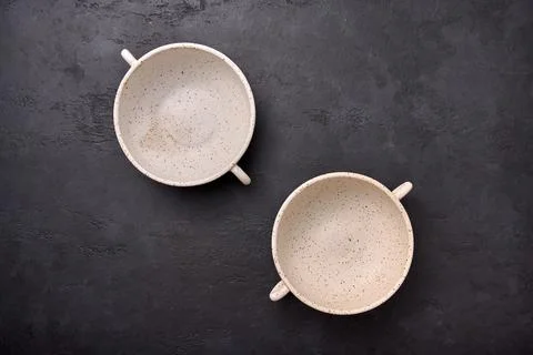 Top view on deep soup bowls with handles on black textured graphite background Stock Photos