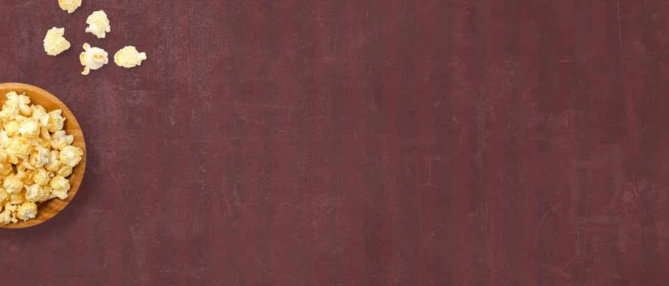 Top view of delicious popcorn on a dark red background with space for text. C Stock Photos