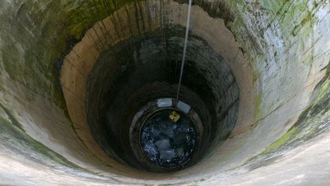 Top view to the depth of a well. Yellow canister with water coming up on 스톡 동영상 127515195