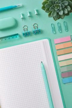 Top view of a desk with mint-colored stationery and an open notepad. Place fo Stock Photos