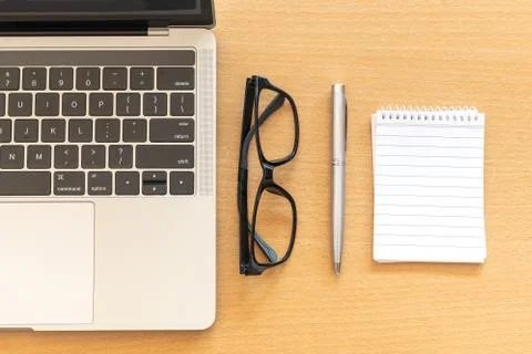 Top view desk with notepad and laptop on office wooden table Stock Photos