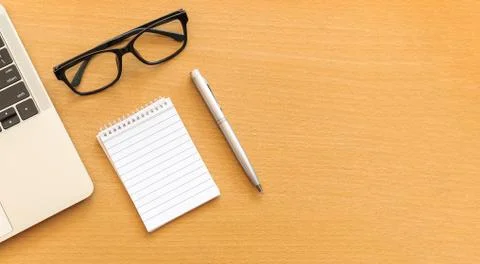 Top view desk with notepad and laptop on office wooden table Stock Photos