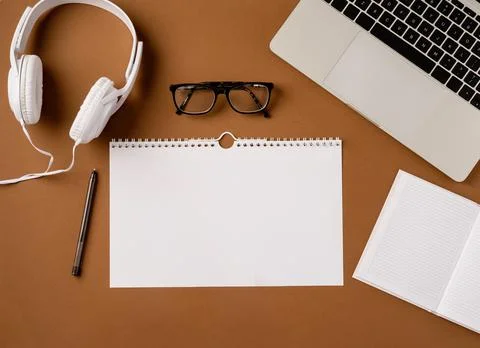 Top view desktop blank calendar, headphones and laptop on light brown backgro Stock Photos