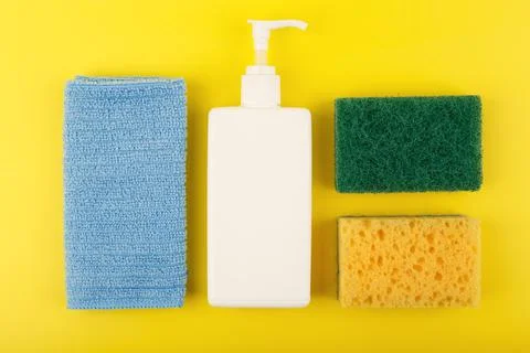 Top view of detergent, dust cloth, cleaning sponge and abrasive sponge on yellow Stock Photos