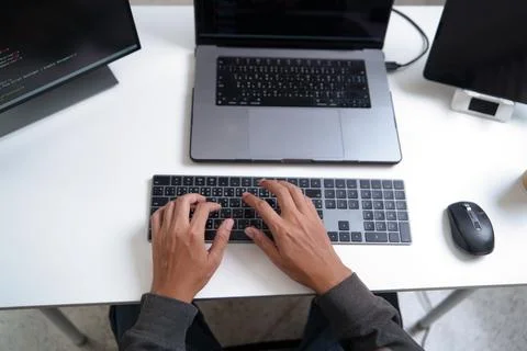 Top View of Developer Working on Laptop with Code on Screen and Keyboard Inpu 库存照片