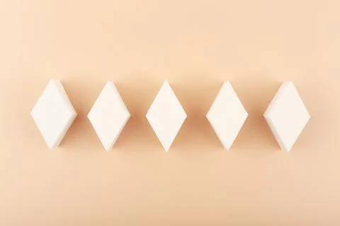Top view of diamond shape make up sponges against beige background Stock Photos