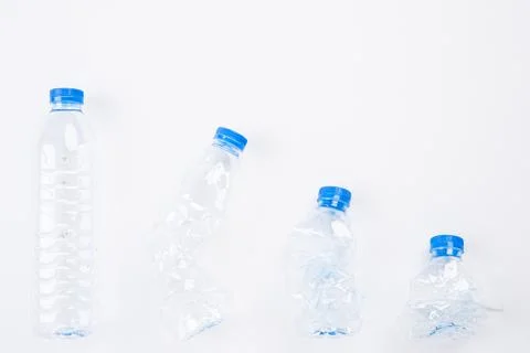 Top view of different empty plastic water bottles from full to crushed on whi Stock Photos