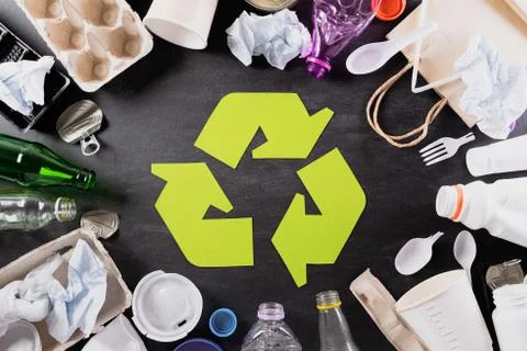 Top view of Different garbage materials with recycling symbol on black backgr Stock Photos