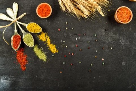 Top view of different kinds of colorful spices in spoons on black stone surface Stock Photos