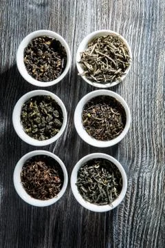 Top view of different kinds of tea leaves in six white small round vessels on Stock Photos