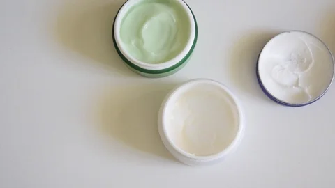 Top view of different opened body/face creams on white background. Cosmetic prod Stock-Footage 88249115