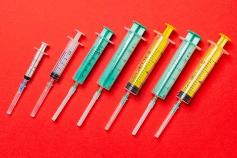 Top view of different syringes at red background. Medical injection concept.. Фото