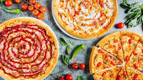 Top view of different types of freshly baked homemade pizzas on a gray surface Stock Photos