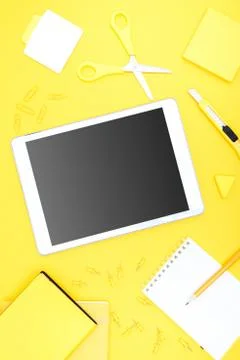 Top view of digital tablet with blank screen and office supplies on yellow ta 写真素材