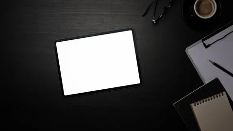 Top view digital tablet with empty screen and supplies on black table. Stock Photos