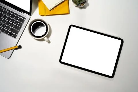 Top view digital tablet with empty display, coffee cup and laptop on white table Stock-Fotos