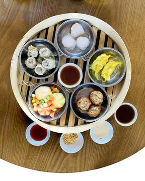Top-view dim sum combination in Chinese bamboo steamer with dipping sauce. Stockfoto's