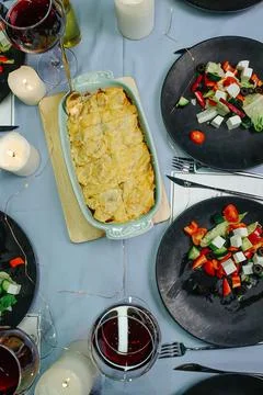 Top view of a dining table with salads, red wine, cooked potatoes and candles Stock Photos