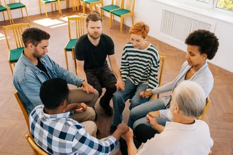 Top view of diverse and different ages people holding hands sitting in circle Stock Photos