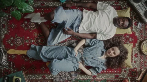 Top View of Diverse Young Couple Lying on Red Vintage Rug and Posing for Camera Stock Footage 339847330