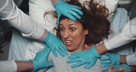 Top view of doctors in latex gloves holding mad screaming woman trying to escape Stock Footage 148228568