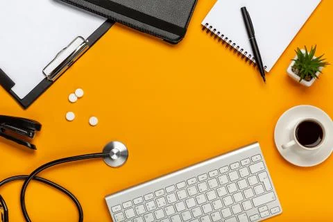 Top view of a doctor's table with notepad and pen stethoscope, keyboard, pres Stock Photos