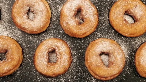 TOP VIEW: Dolly shot of a rows of doughnuts with sugar powder on the black desk Stock Footage 142340366