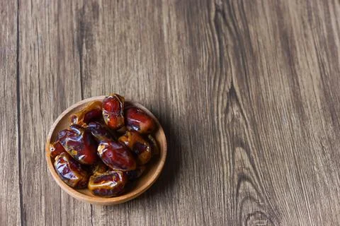 Top view of dried dates served on a wooden bowl. Flat lay, food concept Stock Photos