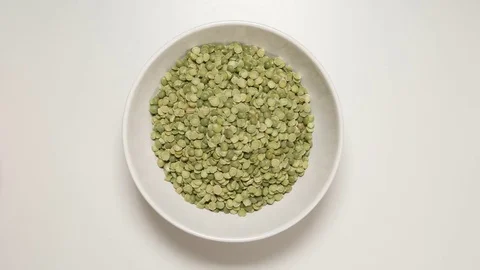 TOP VIEW: Dried green peas fill a white dish (stop motion) Vídeo Stock 69810075