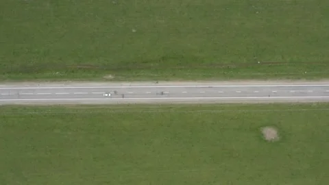 Top view on the driving car of the straight road through the green field. Drone Stock Footage 157017809