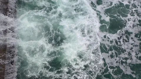 Тop view from drone above of foamy sea waves crashing into a pier Stock Footage 261797705