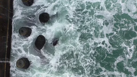 Тop view from drone above of foamy sea waves crashing into a pier with splash Stock Footage 263026423