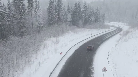 Top view from a drone of a car driving on a snowy Stock Footage 236773014