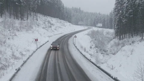 Top view from a drone of a car driving on a snowy Stock Footage 236773637