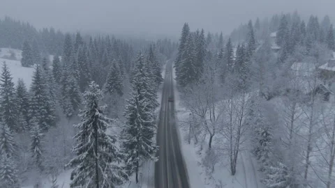 Top view from a drone of a car driving on a snowy Stock Footage 236775048