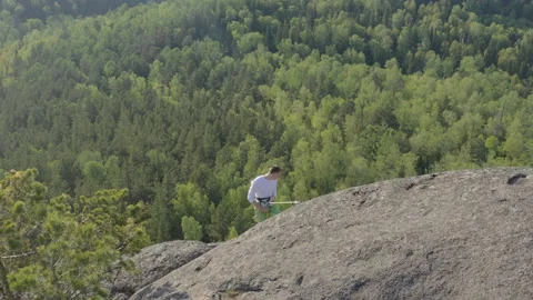 Top view from a drone: a man is extremely descending a rope along a vertical Stock Footage 130896152